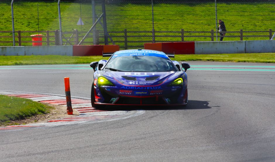 McLaren racing car speeding on Castle Donington track, showcasing agility and design.